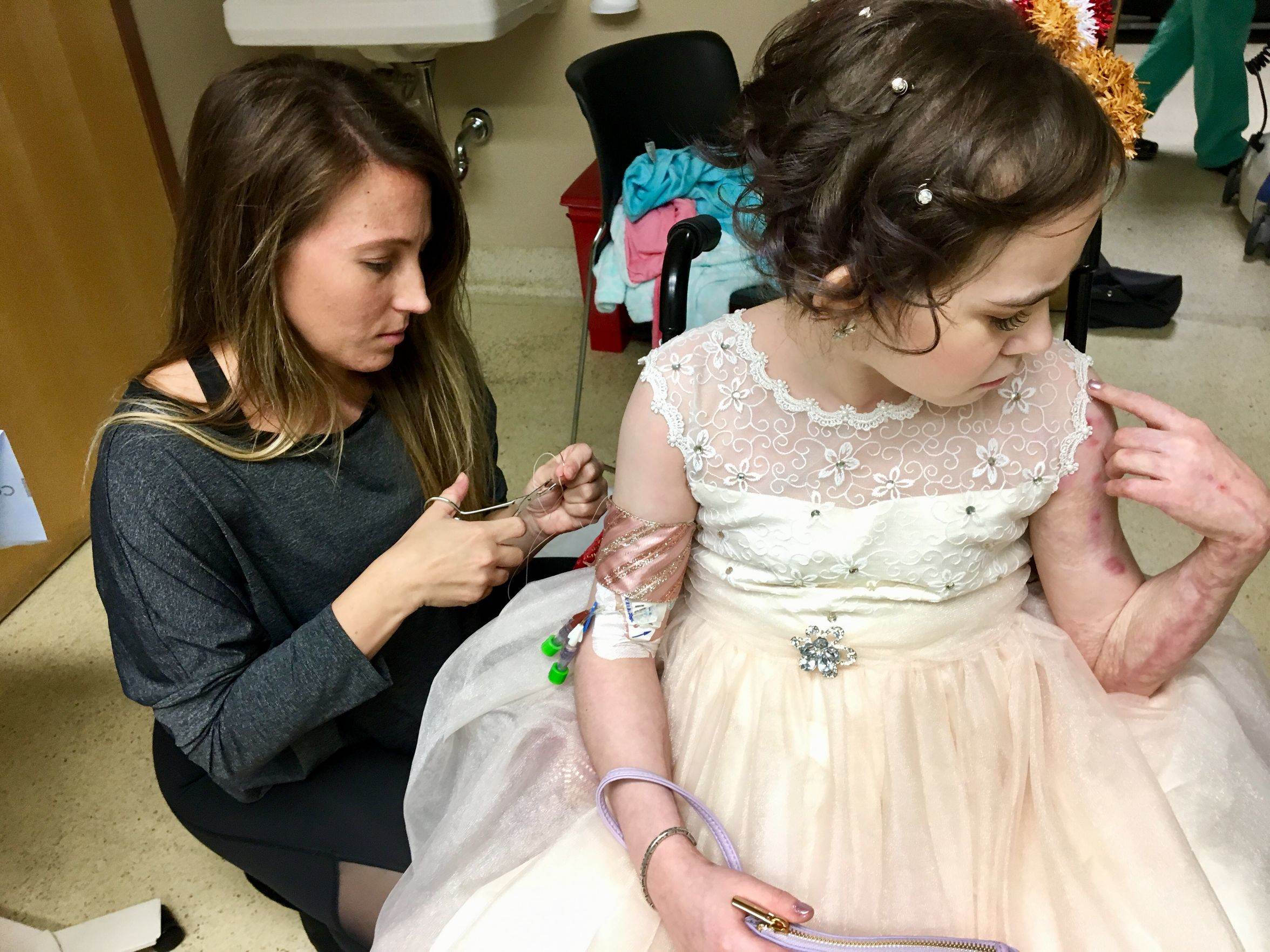 Physician resident Emily Helmick covers Isabella McCune’s the PICC line, a catheter tube in her right arm, with a ribbon, stitching it closed with a suture needle. “You know how to sew?” Isabella asked. “Skin,” Helmick said, making Isabella giggle.