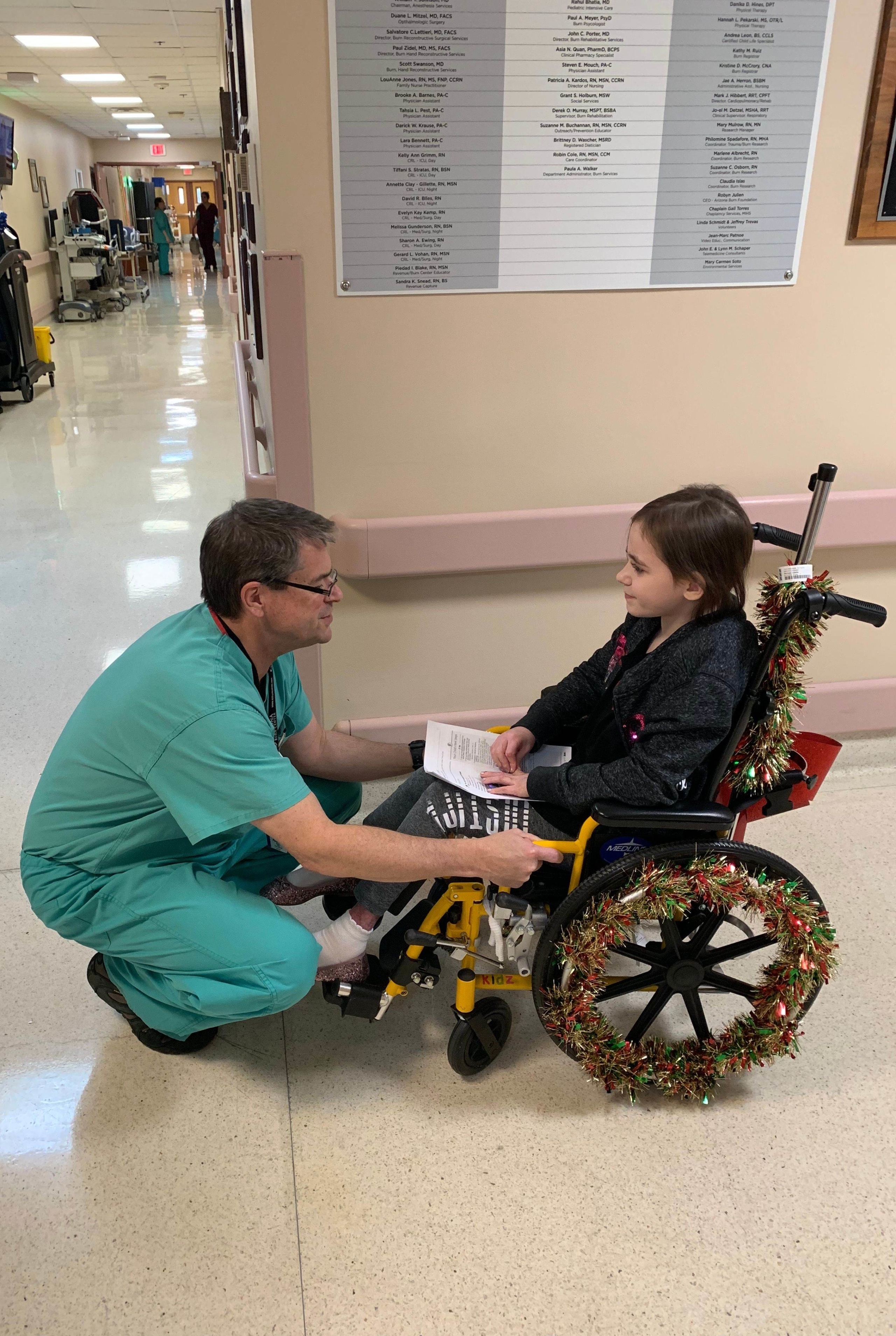 Dr. Kevin Foster, head of the Arizona Burn Center in Phoenix, says goodbye to 9-year-old Isabella McCune as she leaves after nine months in his care. The doctor pushed her wheelchair out to her parents' car.
