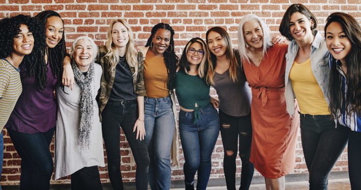 happy group of people in front of brick wall